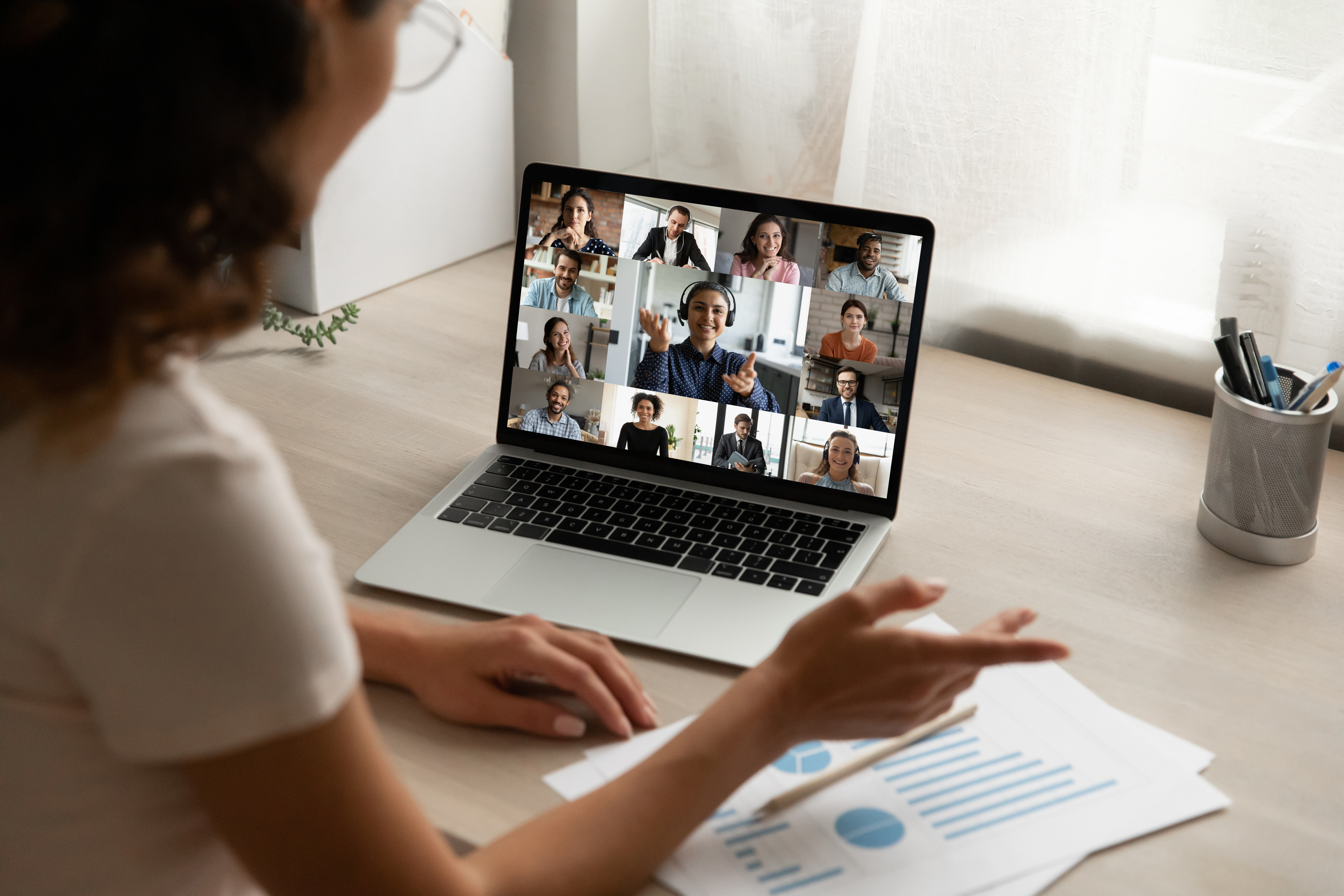 Back view of female speaking on team video call with diverse people, engaged in online group conversation.