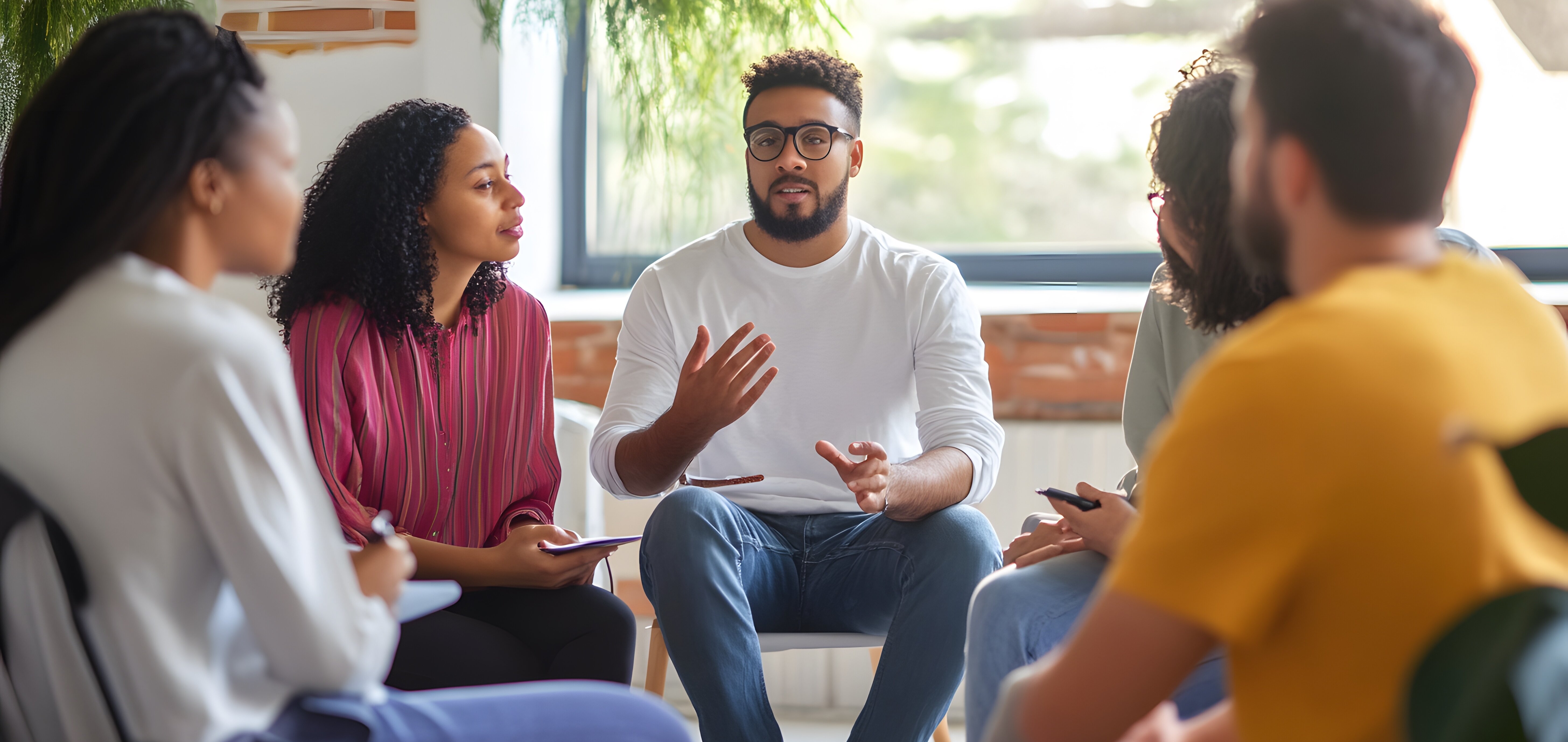 A diverse group of people listen intently as a man speaks.